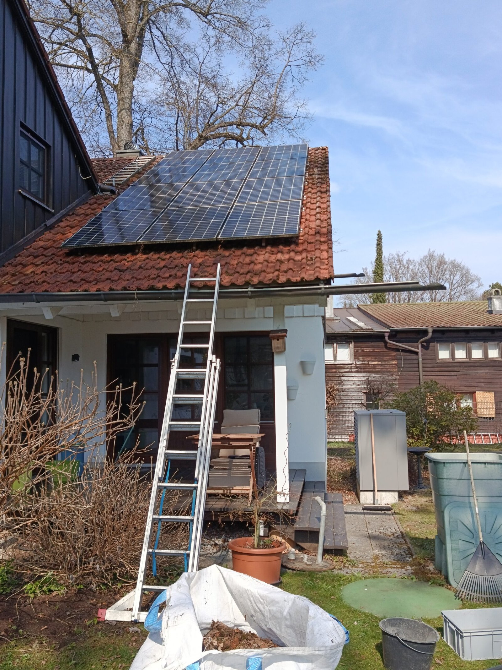 Gewaschene Photovoltaikanlage, Moos entfernt auf Dachschindeln mit Leiter und Gartengeräten in Utting